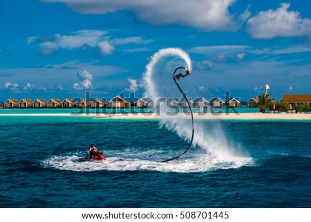 Silhouette of a fly board rider at sea. Professional rider do tricks in the blue lagoon. Tropical water-sport equipment.