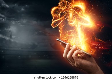 A Silhouette Of A Football Player On Fire Crawls Out Of A Smartphone. Online Sports Concept, Speed, Bet, American Game