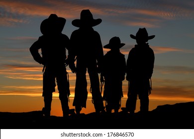 Silhouette of four young cowboys sunset background