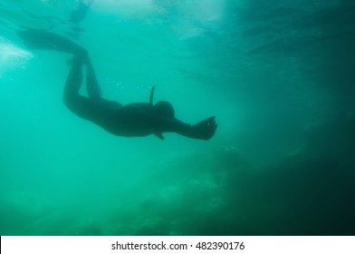 Silhouette of a free diver entering murky environment - Shutterstock ID 482390176