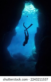 silhouette of free diver woman freediving in cave.