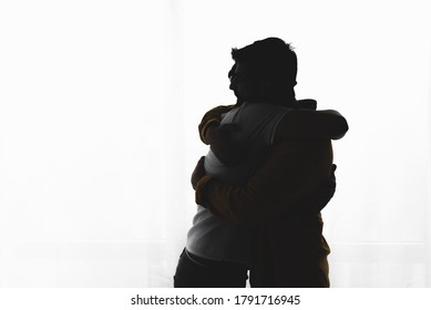 Silhouette Of Gay Couple Embracing Over White Background