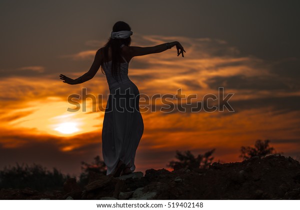 Silhouette of\
a girl dancing Oriental dance at\
sunset.