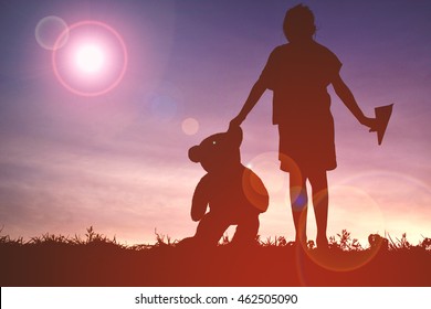 Silhouette girl holding per rocket and teddy bear at sunset. Concept big dream