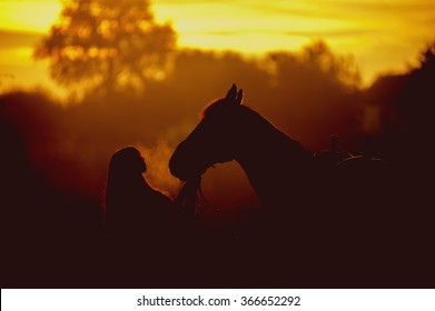 Silhouette of a girl and a horse on a background of dawn. Horse breathing vapor. A man kisses a horse - Powered by Shutterstock