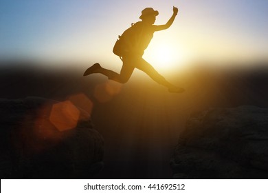 Silhouette girl with the leap over the cliff through difficulties, and excessive to success. in the sunset. Concept big dream to success.