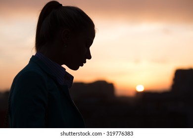 silhouette of a girl on the roof at sunset in the city