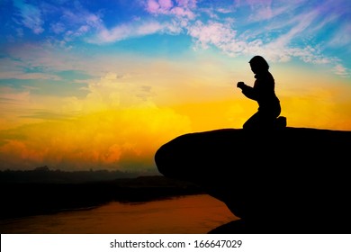 Silhouette of girl praying on the hill