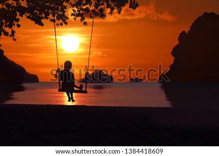 Silhouette of a girl sitting on a swing or cradle on the beach at sunset. Archipelago in Thailand.