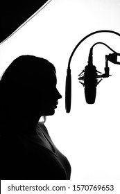 Silhouette of a girl with a studio microphone, Radio presenter, singer and blogger, voice acting for films. Strong, black and white photo. Vertical photo