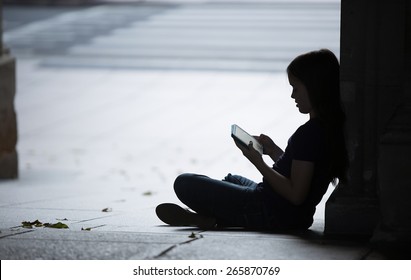 Silhouette Of A Girl Using Her Tablet Computer.  There May  Be A Predator Trying To Get To Her.