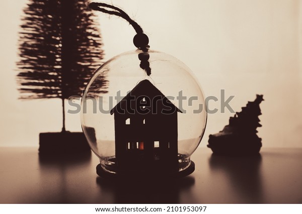 Silhouette of glass round toy lantern, house\
inside for decoration artificial pink Christmas tree, toy car on a\
warm yellow background. New Year 2022. Winter holiday decor.\
Cinematogrophic\
toning