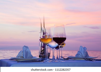 Silhouette glass of wine And equipment on a wooden table with seascape and skyline in the evening with sunset tone style.