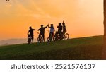 SILHOUETTE: Golden sunset and a group of mountain bikers celebrating on top of the hill after joyful uphill ride. Beautiful autumn day for cycling and exploring the scenic countryside with friends.