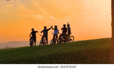 SILHOUETTE: Golden sunset and a group of mountain bikers celebrating on top of the hill after joyful uphill ride. Beautiful autumn day for cycling and exploring the scenic countryside with friends. - Powered by Shutterstock