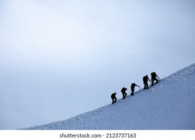 Silhouette Of Group Of Climbers Reaching The Summit