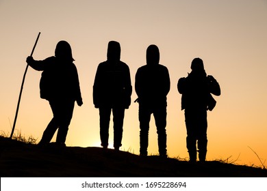 Silhouette Of Group Of Four People Standing At The Hill On Sunset