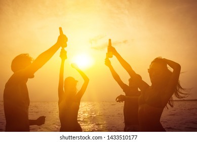 Silhouette Group Of Friends Having Party Celebrating And Drinking At The Beach In Summer Twilight Sunset