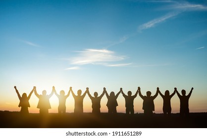 Silhouette of group happy business team making high hands over head in sunset sky background for business teamwork concept.