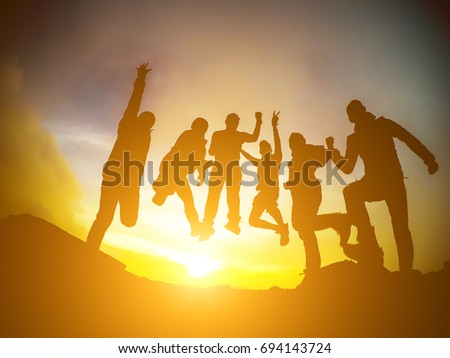 Silhouette group of people jumping over the sunrise.