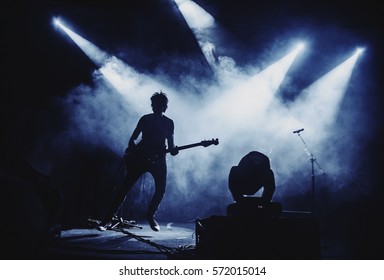 Silhouette Of Guitar Player / Guitarist Perform On Concert Stage. Dark Background, Smoke, Concert  Spotlights