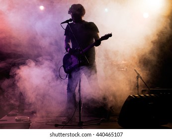 Silhouette of guitar player on stage. Dark background, smoke, spotlights - Powered by Shutterstock