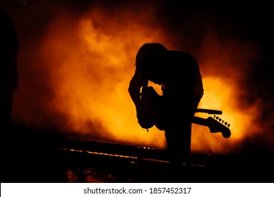 Silhouette Of A Guitar Player In The Smoke. The Guitarist Plays At A Rock Concert.