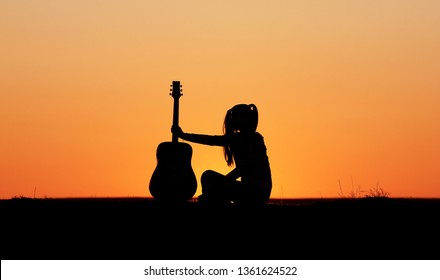 Silhouette of a guitar player at sunset, girl guitarist, silhouette of a guitar, music