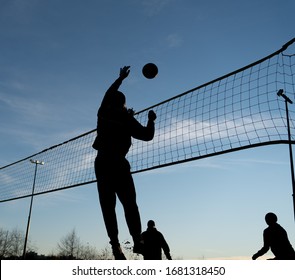 Silhouette Of A Guy In The Sky Bouncing A Volleyball In Front Of The Net.