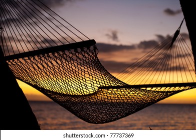 silhouette of hammock on beach overlooking ocean at sunset