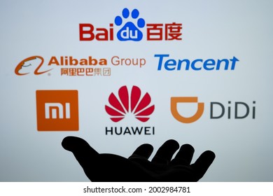 Silhouette Of A Hand And Blurred Chinese Big Tech Companies Logos Baidu Alibaba Tencent Xiaomi Huawei Didi. Concept. Real Photo, Not A Montage. Stafford, United Kingdom, July 6, 2021.