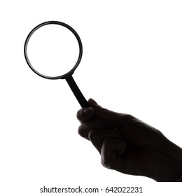 Silhouette of a hand holding a magnifying glass - Shutterstock ID 642022231