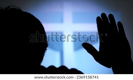 Silhouette Hand raising, blurred christian cross background
