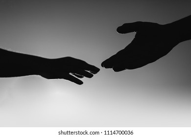 Silhouette of hands of lovers stretching towards each other, hand silhouette at sunset