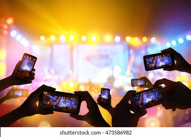 Silhouette of hands using camera phone to take pictures and videos at live concert luxury party.
