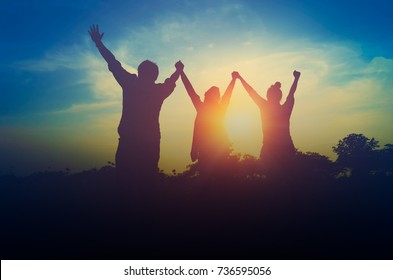 Silhouette of happiness teamwork hold hands up as a business successful, achieve business goal - Shutterstock ID 736595056