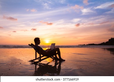 Silhouette Of Happy Business Man With Laptop Working On The Beach
