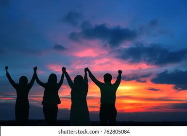 Silhouette Of Happy Business Team Hold Hands Up In Sunset Sky Background, Business Teamwork, Business Achievement  Conceptual