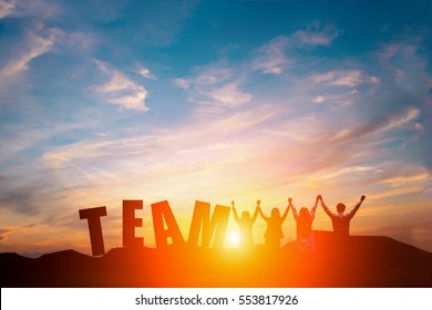 Silhouette Of Happy Business Team Making High Hands In Sunset Sky Background And Text TEAM For Business Teamwork Concept