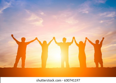 Silhouette Of Happy Business Team Making High Hands In Sunset Sky Background For Business Teamwork Concept.