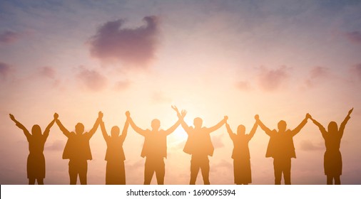 Silhouette of happy business teamwork making high hands over head in sunset sky background for business teamwork concept