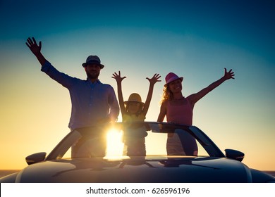 Silhouette Of Happy Family At The Beach Against Sunset Sky And Sea Background. People Traveling By Car. Summer Vacation And Travel Concept