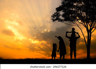 A Silhouette Of A Happy Family Of Five People, Mother, Father,girl,son And Infant (women Pregnancy) With Tree On Blurred Sunset Sky On Mountain (copy Space Or Text On Left Area)