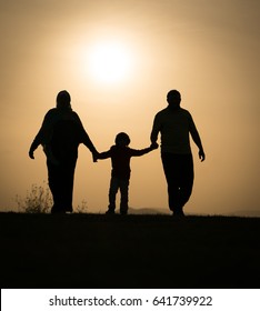 Silhouette Of Happy Family Holding Each Other Hands