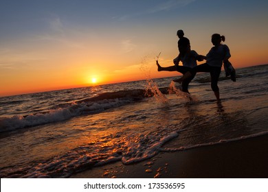 Silhouette Of Happy Family On The Beach At Sunset