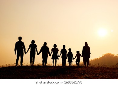 Silhouette Of Happy Family Standing On The Mountain At The Sunset Time.