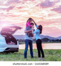 Silhouette The Happy Family Of Three People, Mother, Father And Child In Front Of A Sunset Sky; Asian Family Are Happy Sitting In The Open Trunk Of A Car; Travel Nature Trip.