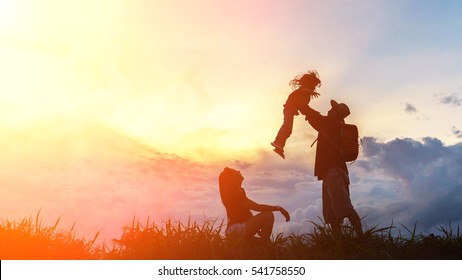 Silhouette The Happy Family Of Three People, Mother, Father And Child In Front Of A Sunset Sky.