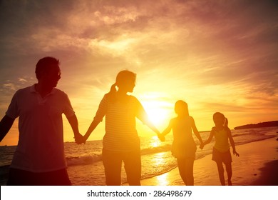 The Silhouette Of Happy Family Walking On The Beach