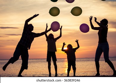 Silhouette Of Happy Family Who Playing On The Beach At The Sunset Time. Concept Of Friendly Family.